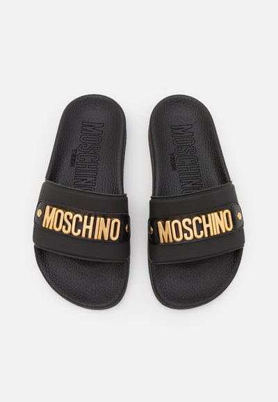 Schwarze Slides aus strukturiertem Material, ausgestattet mit einem breiten schwarzen Riemen mit goldener "MOSCHINO"-Markierung und Akzenten.
