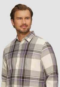 Geruite shirt in tinten van crème, zwart en paars. Gemaakt van zachte stof, met een button-down kraag en een borstzak.