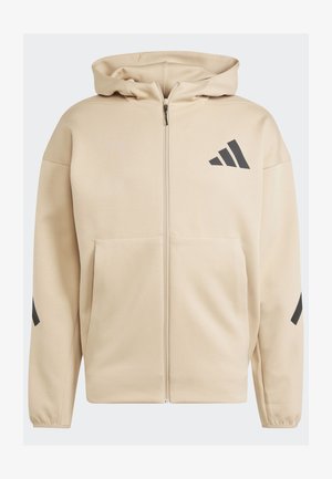 Felpa con zip beige con finitura testurizzata, caratterizzata da un logo Adidas nero e dettagli neri sulle maniche. Design con cappuccio e tasche frontali.