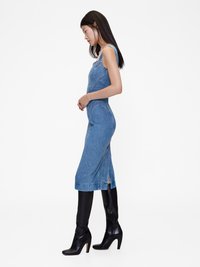 Farmertop, testhezálló sziluettel, térd fölé érő hosszúsággal, oldalhasítékokkal, térdmagasságú fekete magassarkú csizmával viselve. Sima textura, világoskék szín.