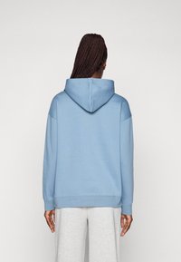 Light blue hooded sweatshirt with a relaxed fit, ribbed cuffs, and hem. Features a large back hood and smooth texture fabric.
