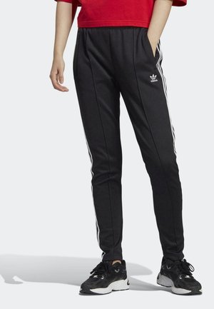 Black sweatpants with white side stripes and Adidas logo; made from soft fabric, featuring an elastic waistband and pockets.