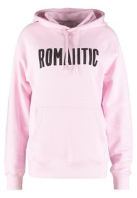 Sudadera rosa con capucha ajustable y bolsillo frontal tipo canguro. Presenta letras negras en negrita "ROMÁNTICO" en el pecho. Textura de tela suave.