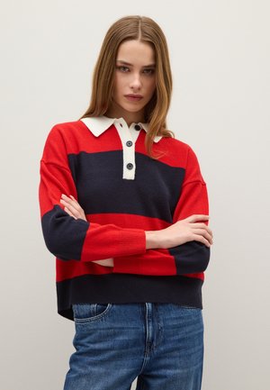 Rood en marineblauw gestreept sweater met een witte kraag en sluiting. Geribbelde manchetten en zoom. Gedragen over blauwe spijkerbroek. Zachte gebreide textuur.