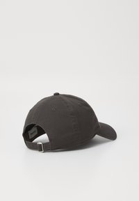 Svart stoff baseballcaps med buet skjerm, justerbar stropp bak og seks paneler. Har ventilasjonsøyler og teksturert stoff.
