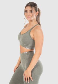 Ljus olivgrön träningsset som består av en åtsittande sport-bh med rynkad front och högmidjade leggings med ribbat mönster och logodetaljer.