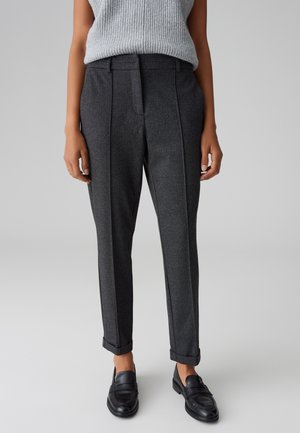 Pantalons gris ajustés en tissu texturé, avec une coupe droite, des ourlets retournés et des plis avant, associés à des mocassins noirs.