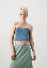 Denim stroppeløs topp med hjerteformet utringning, kort design og blå farge. Sammen med en flytende mintgrønn skjørt.