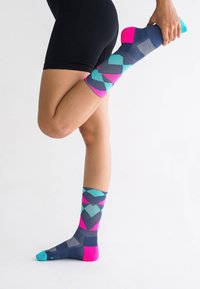 Mehrfarbige knielange Socken mit einem geometrischen Muster in Marineblau, Petrol und Pink; glattes Strickmaterial mit strukturierten Akzenten.