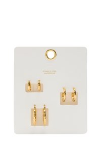 Cztery pary kolczyków ze złotego stali nierdzewnej na białej karcie; obejmuje dwie mniejsze obręcze i dwie większe o młotkowanej teksturze. Wodoszczelne.