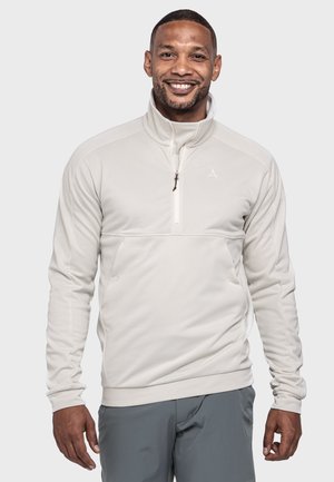 Helles beiges Pullover aus weichem Material, mit einem Reißverschlusskragen, langen Ärmeln und einer schlanken Passform, seitlichen Taschen und einem Logodetail.