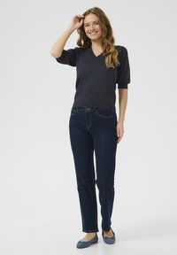 Navy v-neck sweater with short sleeves, paired with dark blue straight-leg jeans and blue flat shoes, featuring a simple design and casual fit.