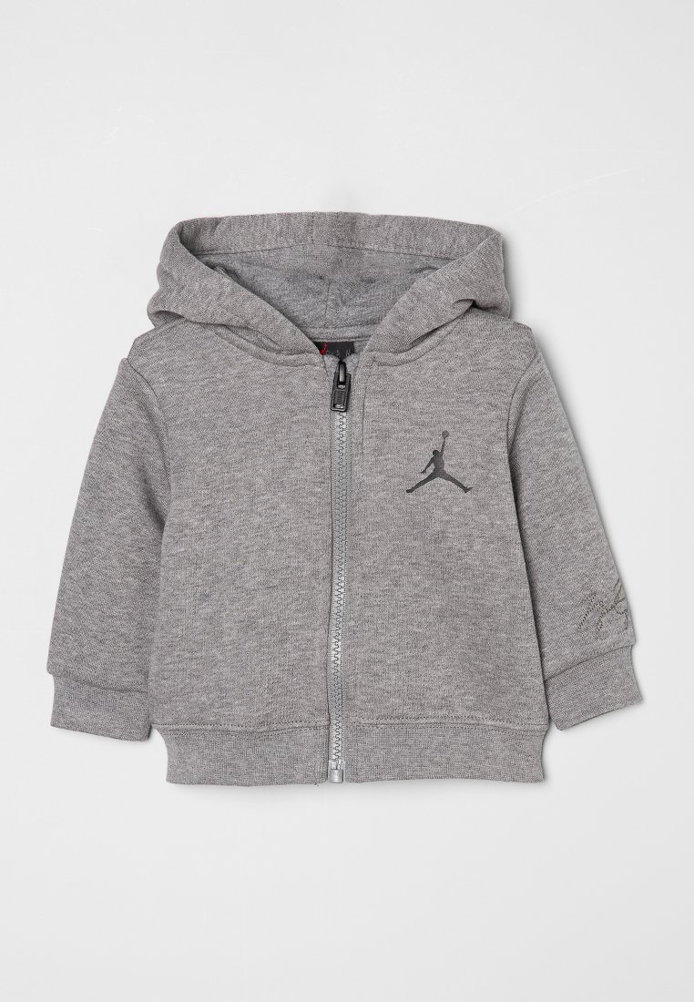 Haut à zip gris en tissu doux, doté d'un petit logo noir Jordan sur la poitrine et d'une capuche avec cordon.