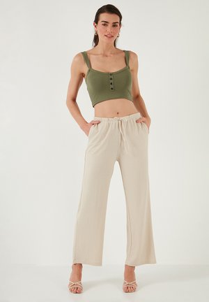 Oliivroheline ribatopy, millel on nuppude detailid, koos beeži lõdva säärega pükstega, millel on elastne vöökoht ja pael.