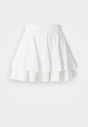 Bijela višeslojna suknja izrađena od lagane tkanine s uzorkom perforacija i volanima na rubu. Ima elastičnu naramenicu za udobnost.