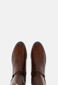 Brown leather knee-high boots with a rounded toe, smooth texture, contrasting stitching, and side buckle accents.