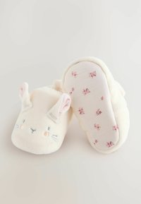 Chaussons en peluche de couleur crème avec des oreilles de lapin, des traits du visage brodés et une semelle douce à motif floral.