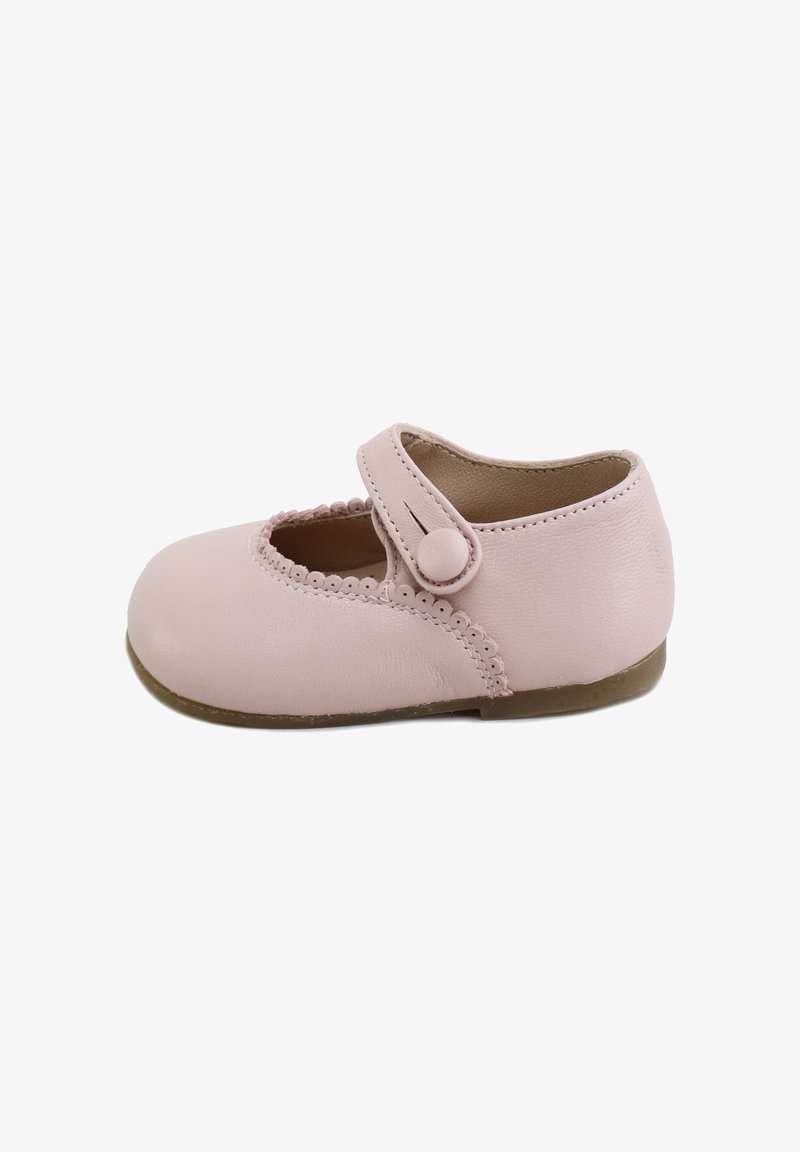 Zapato Mary Jane para niño pequeño en rosa claro con ribete ondulado, una correa con botón redondo y una suela marrón flexible sobre fondo blanco.