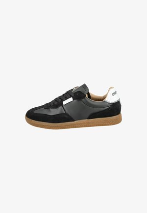 Baskets noires en matériaux en daim et cuir, avec une semelle en caoutchouc, un laçage prononcé et une touche blanche au niveau du talon.
