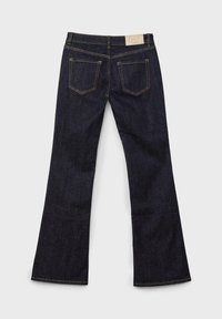 Jean en denim bleu foncé évasé avec un design à cinq poches, des coutures orange et une étiquette en cuir beige à la taille.