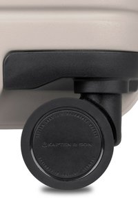 Hartsch suitcase in Elfenbein mit strukturierter Oberfläche, ausgestattet mit einem robusten schwarzen Rad mit Branding. Abgerundet mit einem dunklen Boden und Griff.