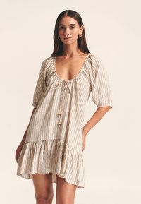 Abito a righe in beige e crema con scollatura profonda, maniche a palloncino, dettaglio con coulisse e orlo a balze a strati.