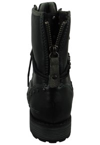 Černá kožená kotníková bota se zadním zipem, texturovaným vzorem a kulatými cvočky blízko spodní části. Má odolnou gumovou podrážku a plochý podpatek.