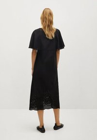 Schwarzes Midikleid mit strukturiertem Oberteil, ausgestellten Ärmeln und dekorativen Ösen am Saum. Hergestellt aus leichtem Stoff.