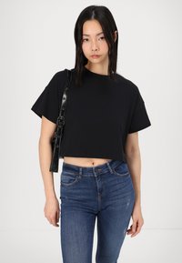 Svart kortärmad t-shirt med rundad halsringning, i kombination med blå denimjeans med en lätt sliten textur och framfickor.