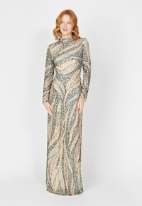 Robe longue en sequins avec un col haut, présentant un motif ondulé dans des tons de vert, or et argent, silhouette ajustée, manches longues.
