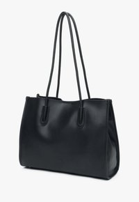 Černá kožená taška přes rameno s dvěma dlouhými uchy, hladkým povrchem a strukturovaným tvarem. Disponuje minimalistickým designem bez viditelného kování.