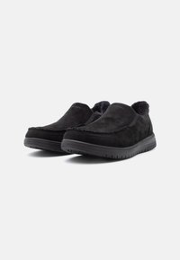 Fekete, velúr anyagú slip-on cipők, puha bélésű belső résszel, kerek orral és texturált gumitalppal. Cérna díszítéssel a szélek mentén.