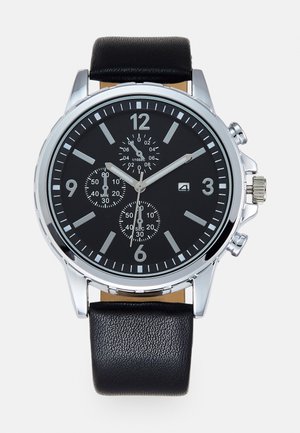 Relógio com bracelete de couro preto e caixa em aço inoxidável prateado. O mostrador preto apresenta marcadores de hora brancos, ponteiros prateados e três submostradores.