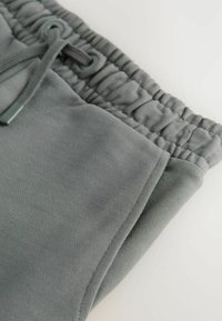 Grå joggers med en mjuk textur, med ett elastiskt midjeband och snörning samt snedställda sidofickor.