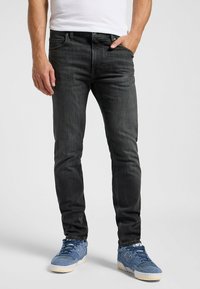 Slim-fit donkergrijze jeans van denim, met een klassiek vijf-pocket ontwerp en subtiele vervaging. Gepaard met blauwe sneakers.