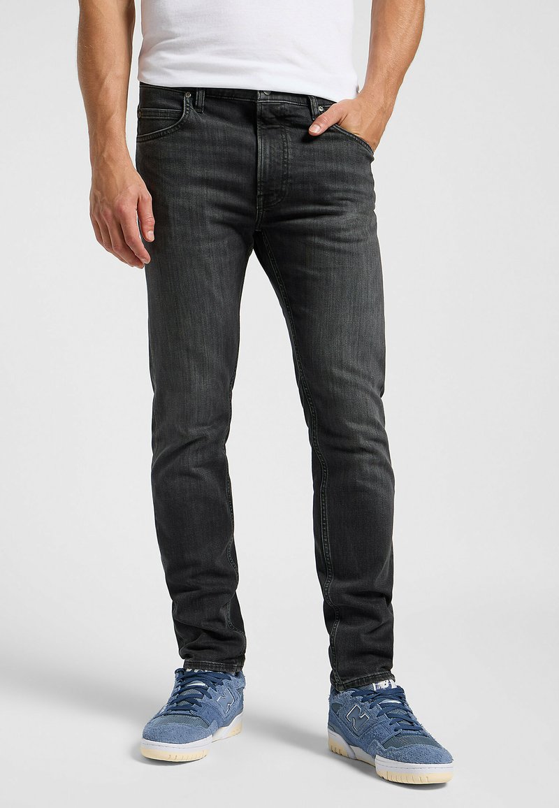 Slim-fit donkergrijze jeans van denim, met een klassiek vijf-pocket ontwerp en subtiele vervaging. Gepaard met blauwe sneakers.