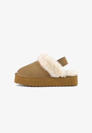 Brown suede slide slipper with fluffy cream faux fur trim, a thick platform sole, and a back strap for support. Textured grip on the sole.