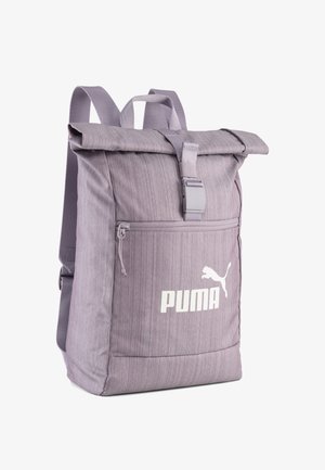 Sac à dos violet à rabat, fabriqué en tissu texturé, avec une poche zippée à l'avant et un logo Puma blanc. Sangles réglables et fermeture à boucle.