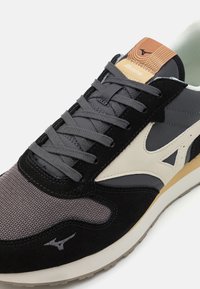 Black and grey sneaker with suede and mesh upper, grey laces, beige accents, and a brown logo tag on the tongue. Rubber outsole.