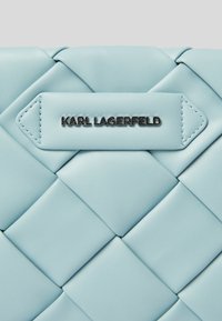 Miękka, jasnoniebieska torebka ze skóry pikowanej z srebrną plakietką z logo "KARL LAGERFELD" oraz wyraźnymi wzorami plecionki.
