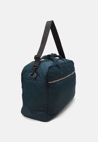Geantă de voiaj albastră, captusită, cu fermoar de sus, curea din material textil detașabilă și mânere superioare. Dispune de o buzunar frontal cu fermoar și un design elegant, rotunjit.