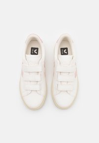 Hvite sneakers med rosa detaljer og borrelås, med rund tå, teksturert skinnmateriale og en beige gummisåle.