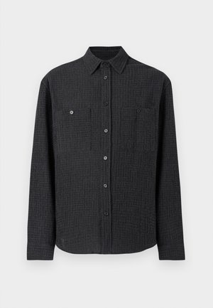 Črna srajca z gumbom, izdelana iz teksturirane tkanine, z dvema prsnih žepoma in s koničastim ovratnikom. Dolgi rokavi z gumbastimi manšetami.