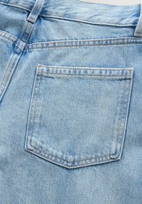 Poche arrière d'un jean en denim bleu clair avec coutures visibles et passants de ceinture.