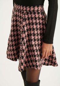 Rosa und schwarze kariertete Röhre aus strukturiertem Stoff; ausgestelltes Design mit elastischem Bund. Details umfassen eine weiche Oberfläche und einen knielangen Schnitt.