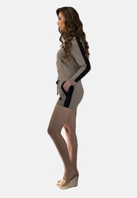 Beżowy zestaw sportowy z krótką bluzą z kapturem i czarnymi panelami bocznymi oraz pasującymi szortami. Miękki materiał, elastyczny pasek w talii oraz boczne kieszenie.