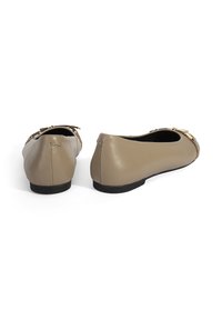 Beige Leder Ballerinas mit runder Zehenpartie, kleinem schwarzen Absatz und dekorativen goldenen Hardware-Accents. Glatte Textur mit minimalen Nähdetails.