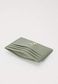 Green leather card holder with a textured finish, featuring multiple card slots and a gold-tone logo accent on the front.