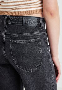 Sorte denim jeans med høj talje, som har en struktureret overflade, baglommer og et mærket læderpatch med "Lee"-logoet.