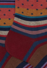 Striped and polka dot patterned knitted socks in red, mustard, blue, pink, and brown tones overlapping each other.